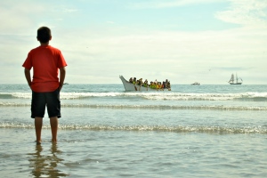 A boy looks on as a tribe arrives on the Quinault shores.